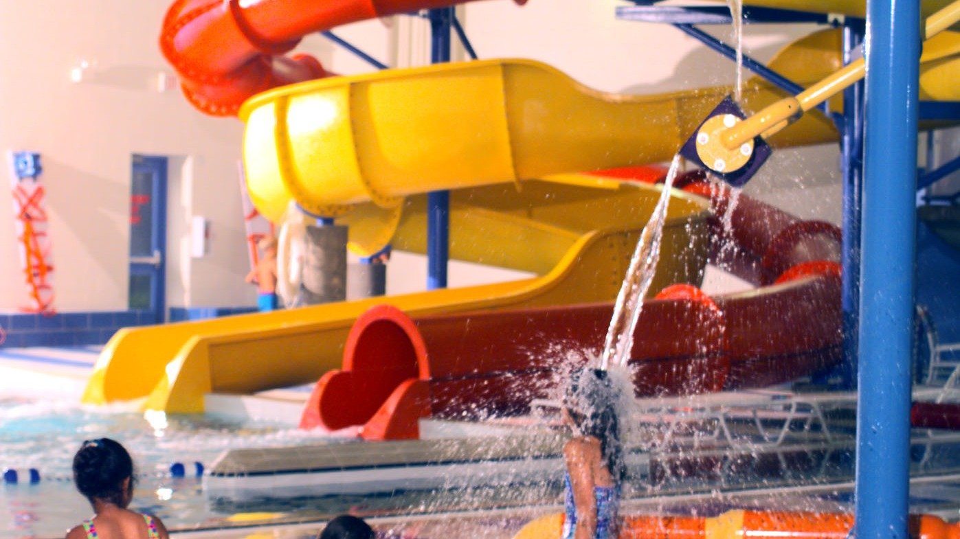 An enclosed indoor waterslide tower descending toward a pool