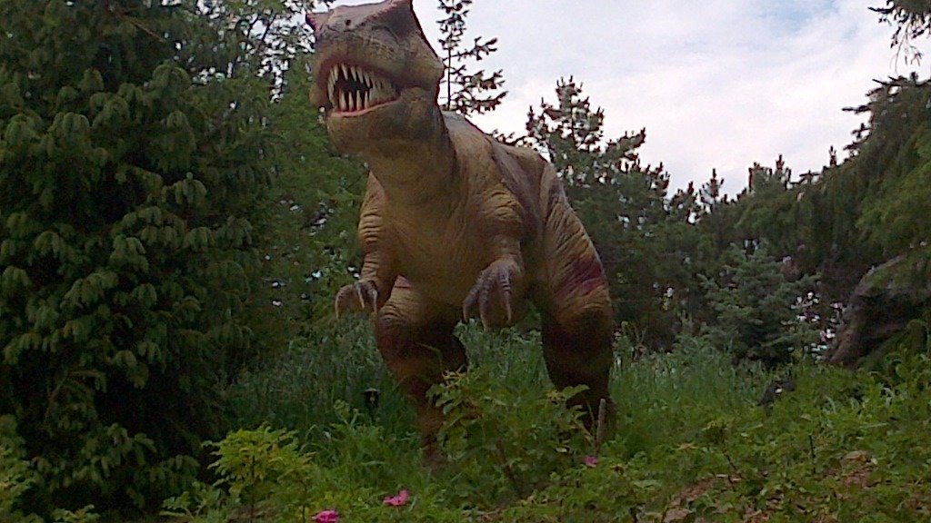 The entrance to a dinosaur-themed family attraction, featuring large dinosaur models