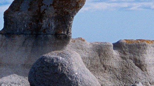 Squat mushroom-shaped limestone sea stacks rising from shallow turquoise water in the Mingan Archipelago